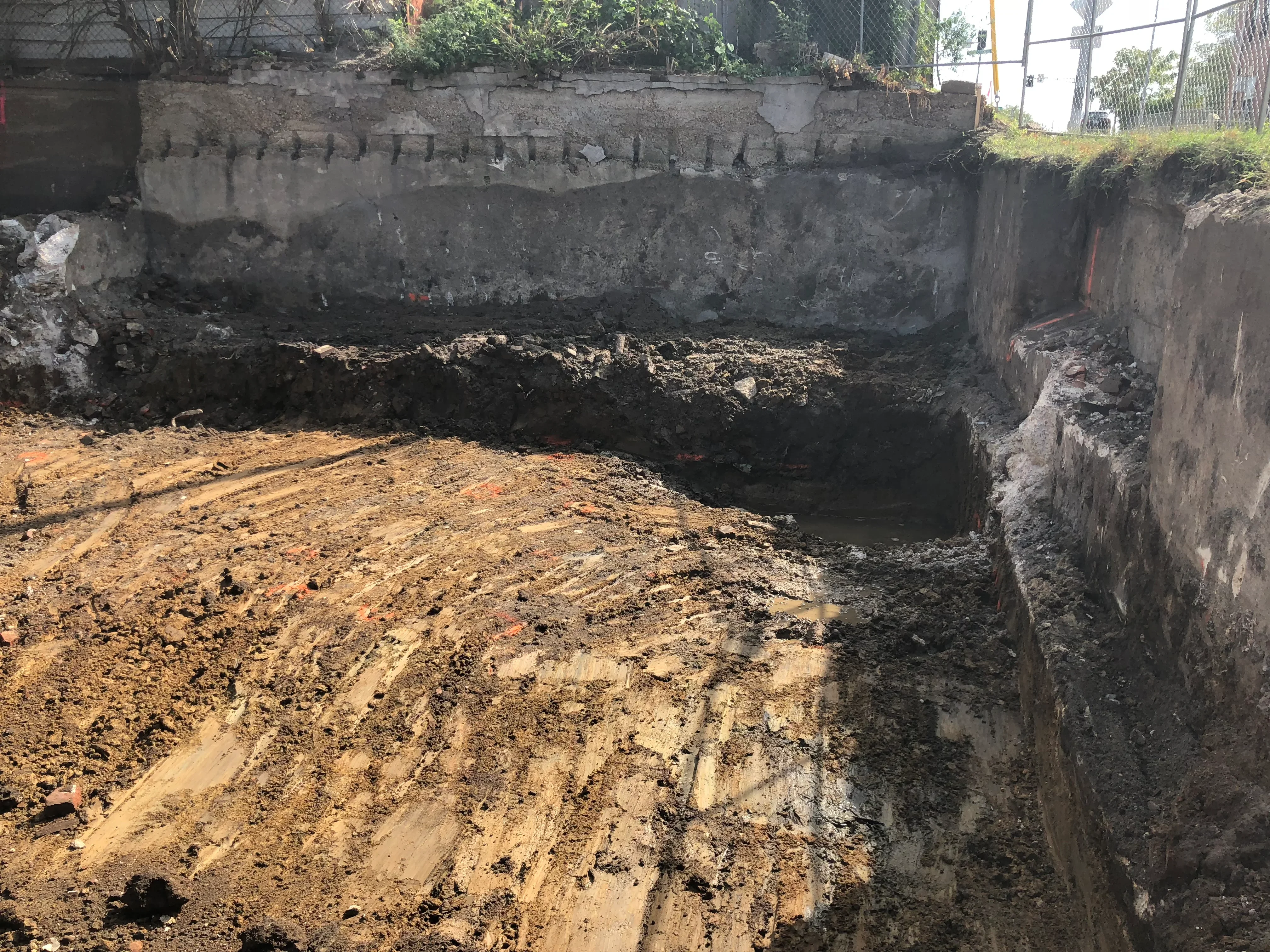 Demolished concrete foundation with exposed soil and debris removal in excavated site