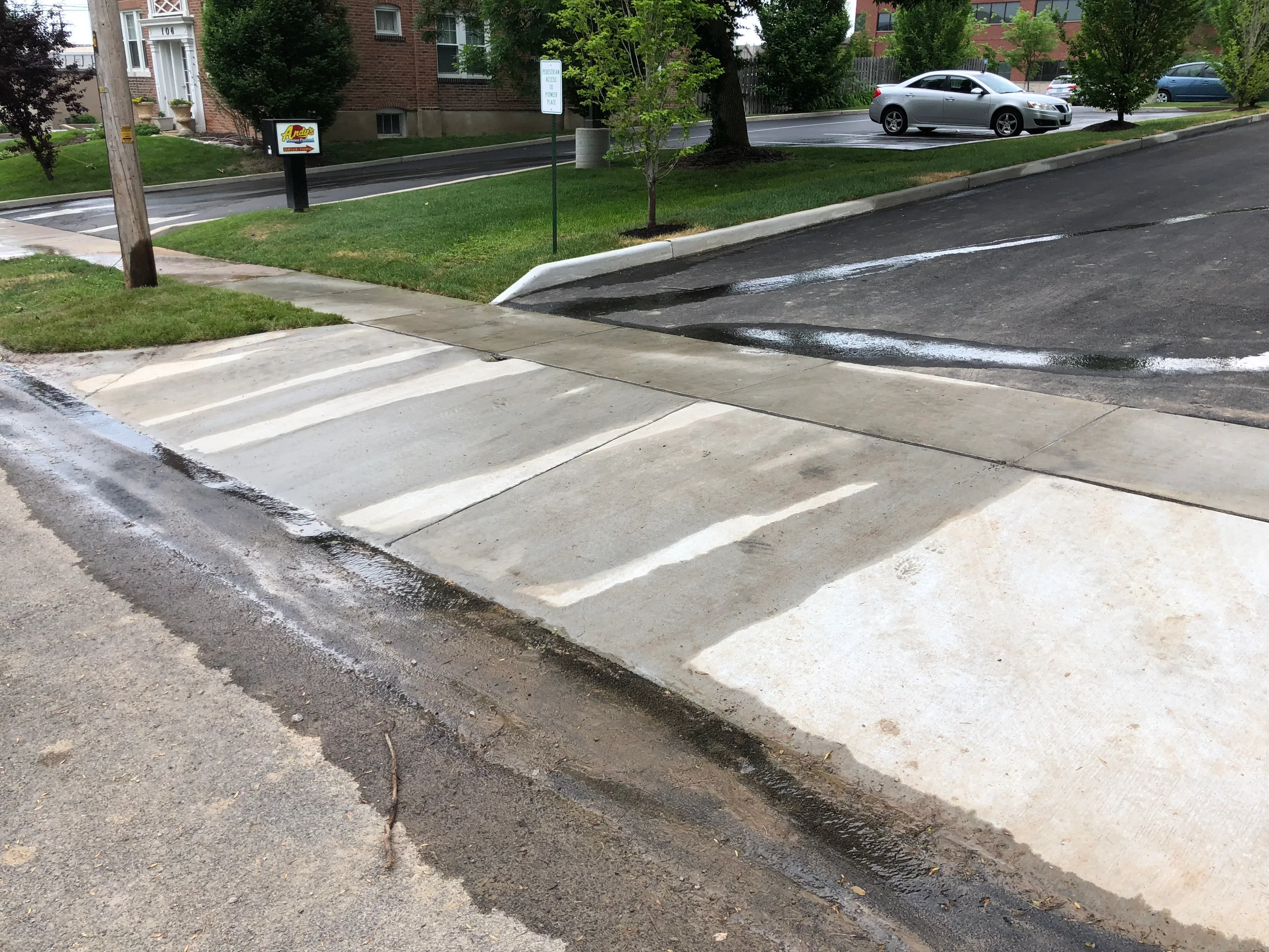 Concrete driveway demolition with removed slabs and debris staging along residential street